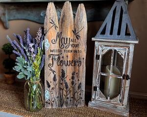 A Wood-burned fence gate wall decoration with dragonflies and the phrase "may all your weeds turn into flowers" on the front.